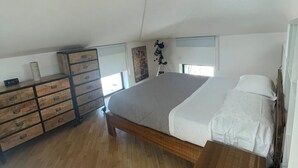 A bedroom with a wooden bed, a dresser, and a ceiling fan. - Cozy Studio in the Heart of Franciacorta - Base for Lake Iseo (Passirano)