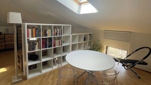 A room with a skylight, a white bookshelf, a round table, and clear chairs. - Cozy Studio in the Heart of Franciacorta - Base for Lake Iseo (Passirano)
