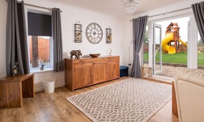 A room with a wooden cabinet, a patterned rug, and a view of a playground.