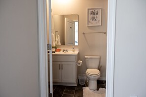A bathroom with a toilet, sink, and mirror. There is a towel rack and a trash can. - Holistic Campus Rental, LLC - Entire Home (Oxford)