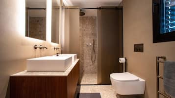 A modern bathroom with a wooden vanity, a white sink, a shower, and a toilet.