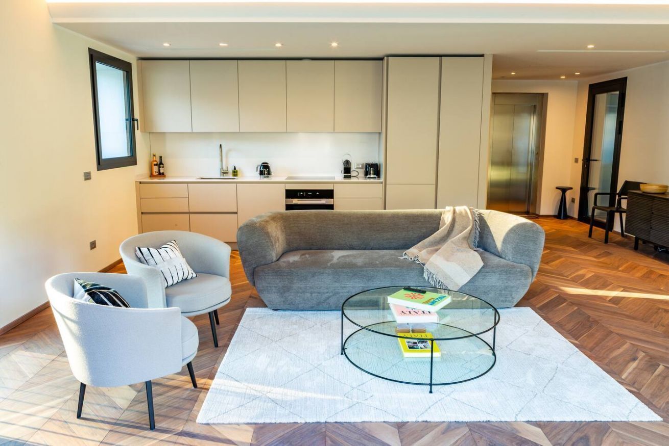 A modern living room with a sofa, armchair, and glass coffee table.