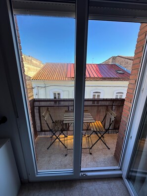 A balcony with a view of a building with red-tiled roofs and a wooden fence.