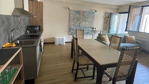 A modern kitchen with a dining area, wooden cabinets, and a large painting on the wall. - Villa Valle Franciacorta - Green Apartment with Pool and Garden (Rodengo-Saiano)