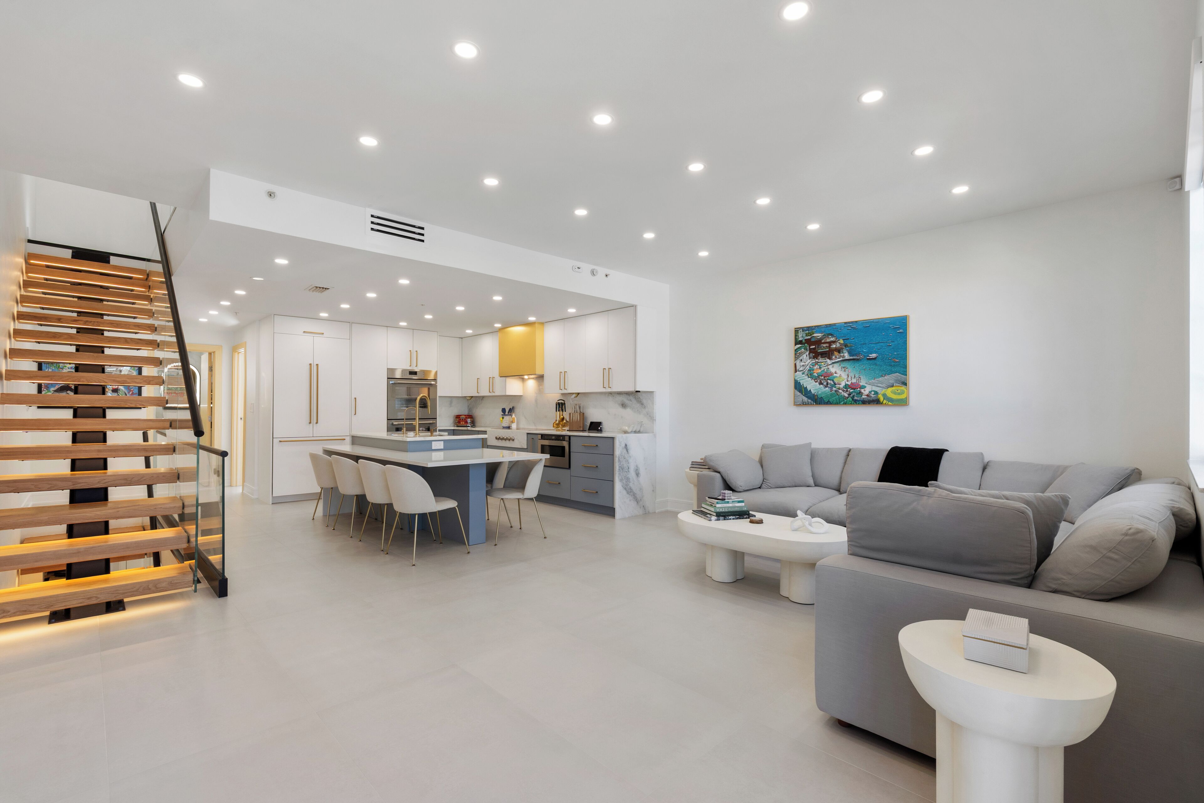 Una sala de estar moderna con un sofá gris, una mesa de centro y un comedor con una cocina al fondo.
