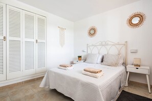 Ein Schlafzimmer mit Bett, weißen Vorhängen, einem Nachttisch mit Lampe und Wanddekoration.