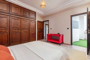 Ein Schlafzimmer mit einem großen Bett, einem Holzschrank und einer roten Unterhaltungsecke.