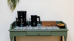 Una cocina con cafetera, hervidor y una caja de té sobre una mesa verde.