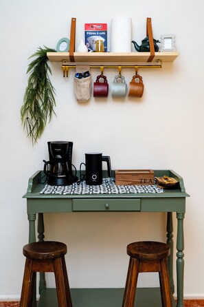 Eine Küchenzeile mit einer Kaffeemaschine, einem Wasserkocher und einer Teeaufbewahrungsbox auf einem grünen Tisch.