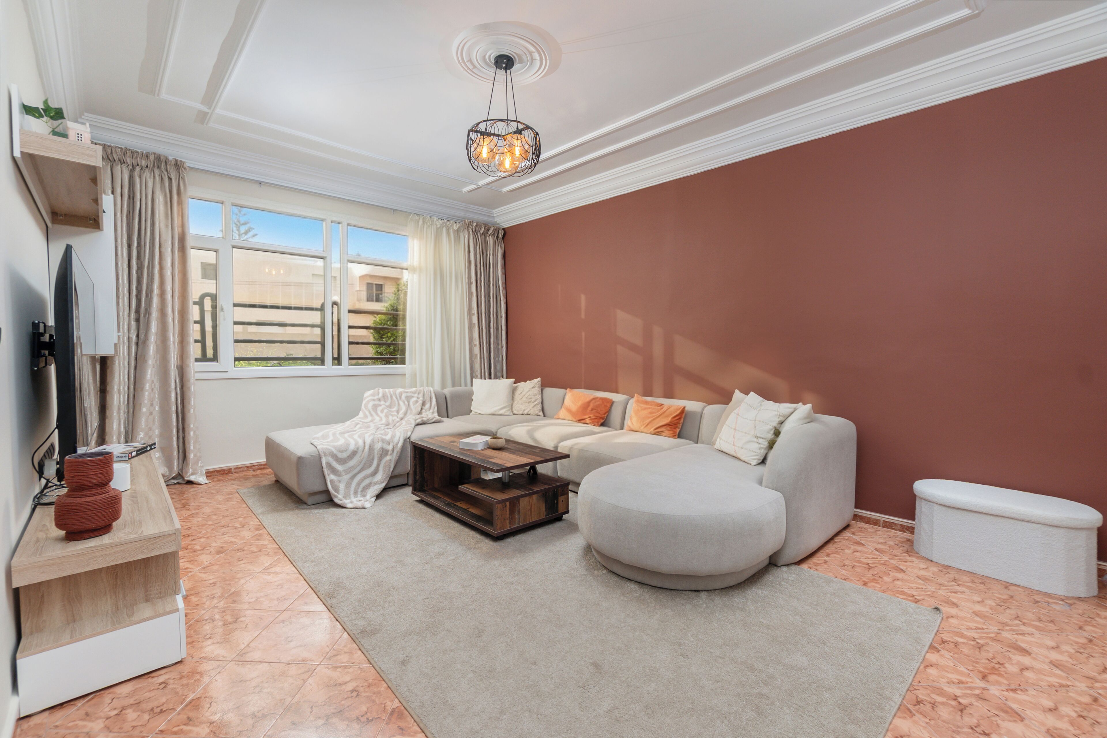 A modern living room with a sectional sofa, a coffee table, and a TV on a stand.