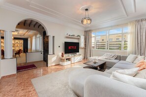 Ein modernes Wohnzimmer mit großem Fernseher, einer Couch und einem Couchtisch.