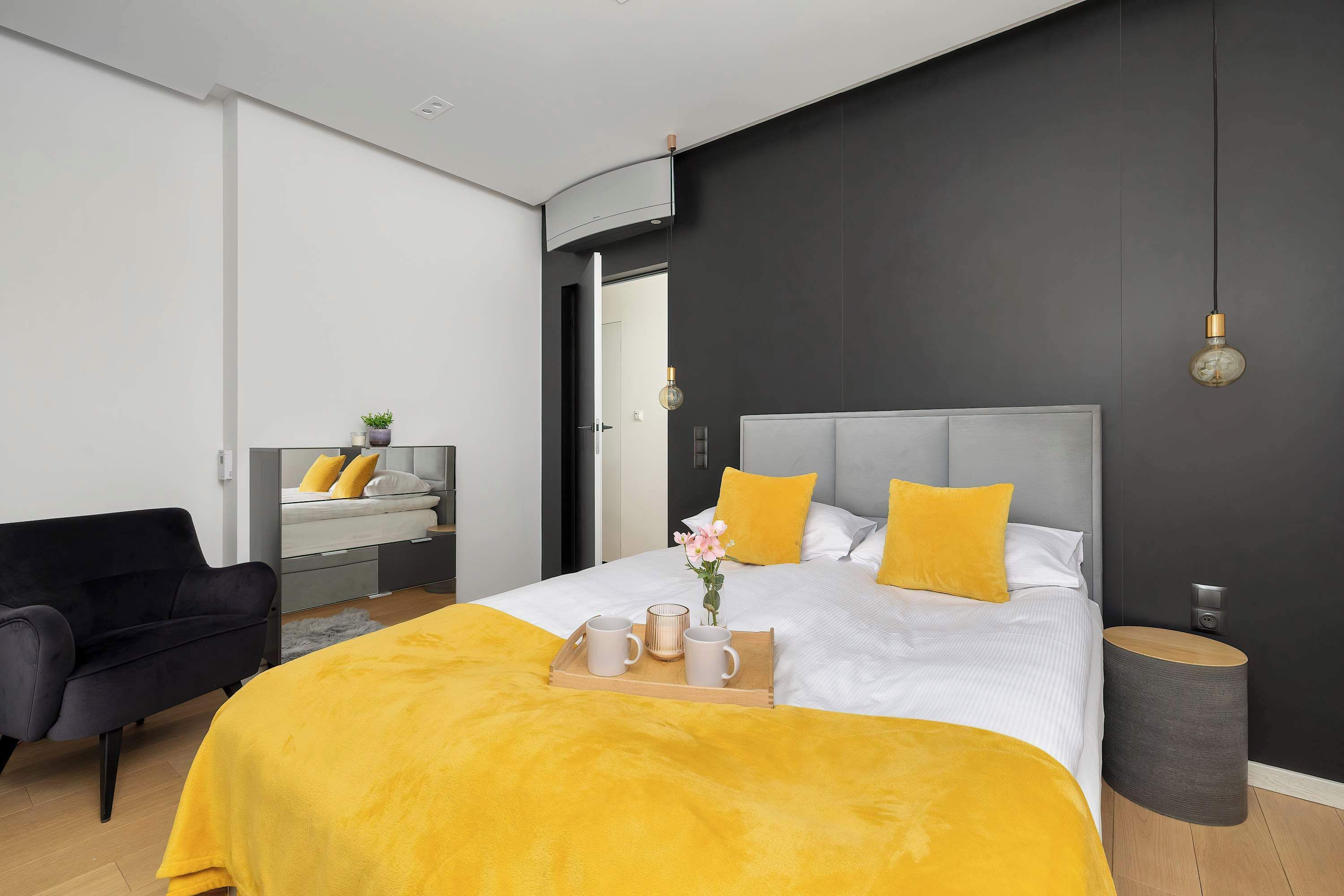 A modern bedroom with a large bed, a bedside table, a chair, and a small round table.