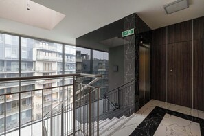 Ein modernes Interieur mit einem Glaselevator, einem Marmorboden und Blick auf umliegende Gebäude.
