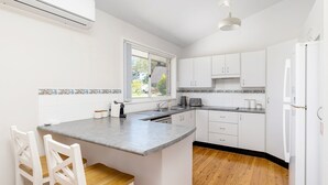 Een moderne keuken met witte kastjes, een grijze aanrecht en een raam dat natuurlijk licht binnenlaat.