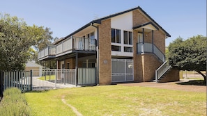 A two-story building with a balcony on the upper floor, a staircase on the right, and a fenced front yard. - Port View on the Peninsula (Lemon Tree Passage)