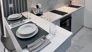 Uma cozinha moderna com bancada branca, duas pias e forno embutido.