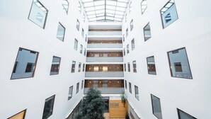 A multi-level atrium with a glass ceiling, multiple balconies, and a central staircase. - RentPlanet - Kazimierza Wielkiego (Poznań)