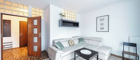 Un salon moderne avec un canapé d’angle, une table basse et une étagère fixée au mur.