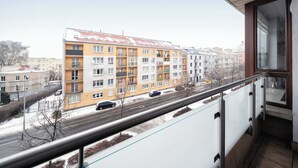 A balcony with a metal railing overlooking a multi-story residential building with balconies. - RentPlanet - Kazimierza Wielkiego (Poznań)