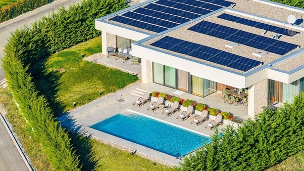 Una casa moderna con piscina, pannelli solari e un giardino curato.