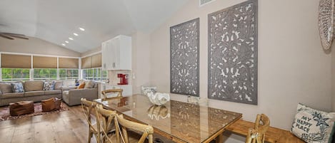 A spacious living area with a large wooden dining table, comfortable seating, and decorative wall art.