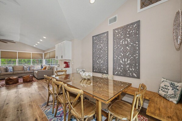 A spacious living area with a large wooden dining table, comfortable seating, and decorative wall art. - 3 min walk to beach/Heated Pool/Games/Kids area (Clearwater Beach)