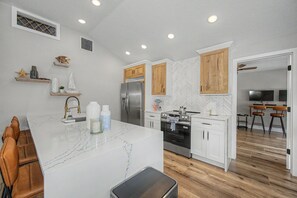 A modern kitchen with white cabinetry, a marble island, and wooden accents. - 3 min walk to beach/Heated Pool/Games/Kids area (Clearwater Beach)