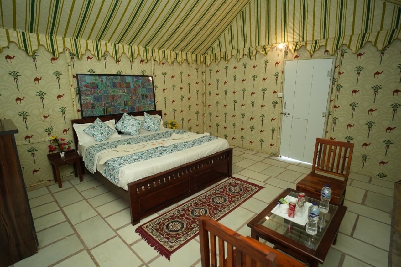 A bedroom with a bed, a nightstand, a chair, a table, and a door.