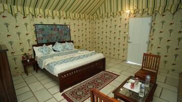 A bedroom with a bed, a nightstand, a chair, a table, and a door.