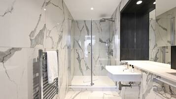 A modern bathroom with a glass-enclosed shower, a white sink, and a large mirror.