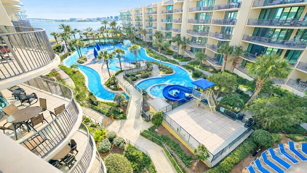 Un resort con una grande area piscina, diversi balconi e vista sul mare.
