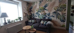 A cozy living room with a dark sofa, a small round table, and a radiator. - 20% off on the first Sunday of All Saints' Day. Large 130-square-meter duplex • 6 bedrooms with made-up beds. Patio & Parking Lot (La Bresse)