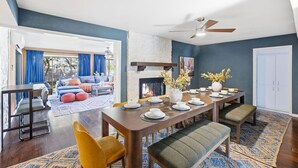 A dining area with a fireplace, a dining table set for four, and a view of a blue living room with a sofa and curtains. - Resort Oasis w/ Pool | Hot Tub | Mini Golf & Games (San Antonio)