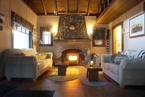 A cozy living room with two sofas, a fireplace, and a stone accent wall. - Secluded Forest Cabin in Rhododendron near Mt Hood Village in Oregon (Rhododendron)