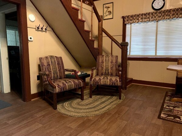 A room with a wooden staircase, two patterned chairs, a small table, and a clock on the wall. - Secluded Forest Cabin in Rhododendron near Mt Hood Village in Oregon (Rhododendron)