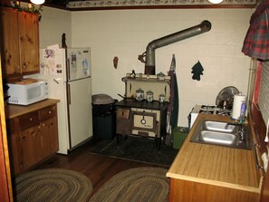 A compact kitchen with a wood stove, a sink, and a microwave. - Secluded Forest Cabin in Rhododendron near Mt Hood Village in Oregon (Rhododendron)
