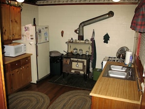 A compact kitchen with a wood stove, a sink, and a microwave. - Secluded Forest Cabin in Rhododendron near Mt Hood Village in Oregon (Rhododendron)