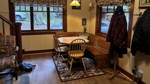 A dining area with a wooden table and chairs, a bench, a clock, and a window with a view of the outdoors. - Secluded Forest Cabin in Rhododendron near Mt Hood Village in Oregon (Rhododendron)