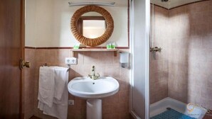 Un baño con lavamanos, espejo y ducha.