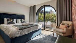 Une chambre avec un grand lit, une chaise et une vue sur l’extérieur, visible à travers une porte vitrée.