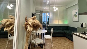 Una sala de estar moderna con un sofá verde, una mesa de comedor con sillas y una zona de cocina.