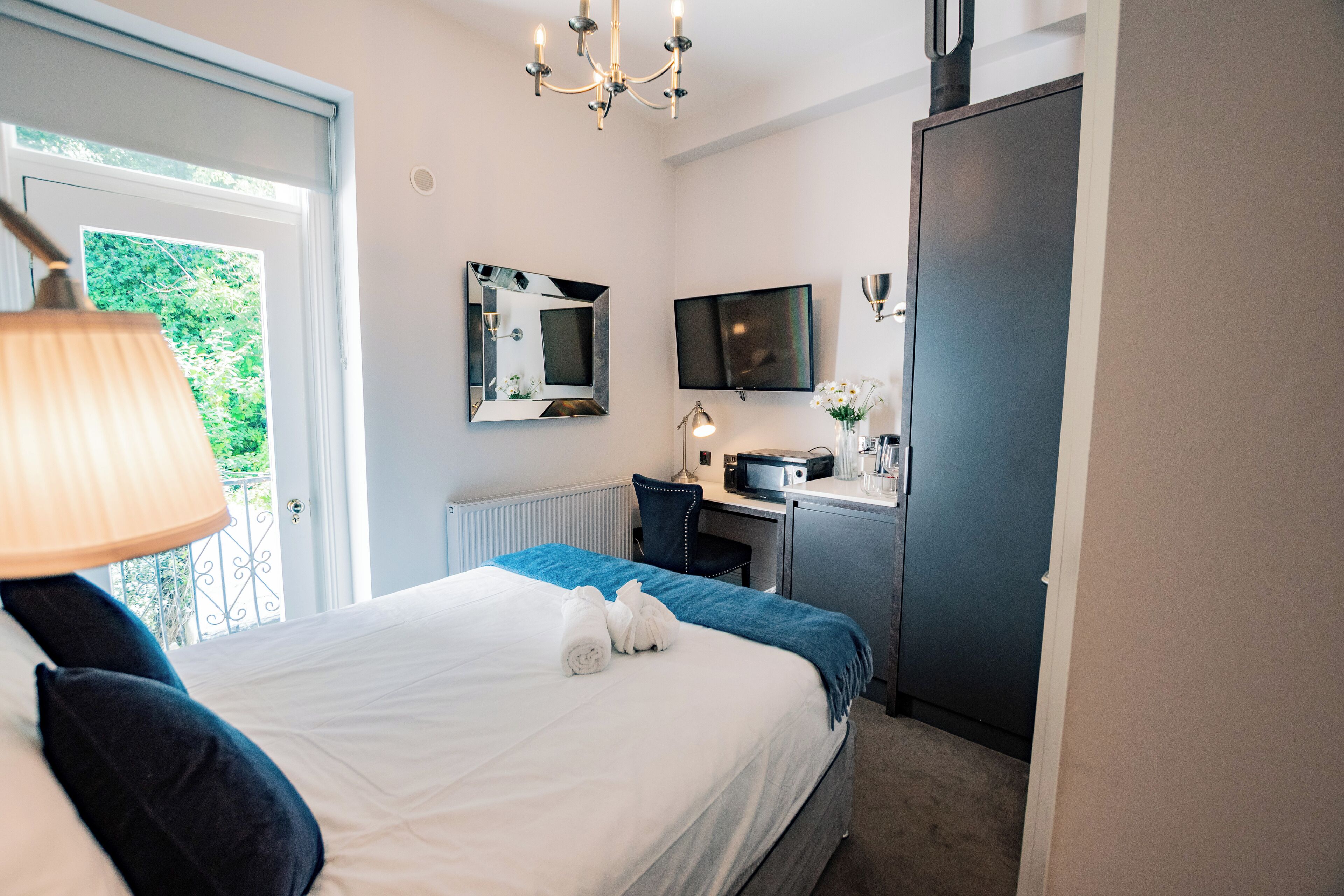 Une chambre d’hôtel avec un lit, un bureau, une télévision et une fenêtre.