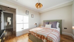 Ein Schlafzimmer mit Bett, Fenster, Tür und einer Deckenleuchte.