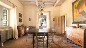 Ein Esszimmer mit Holztisch, Stühlen, einer Kronleuchter und einem Gemälde an der Wand.