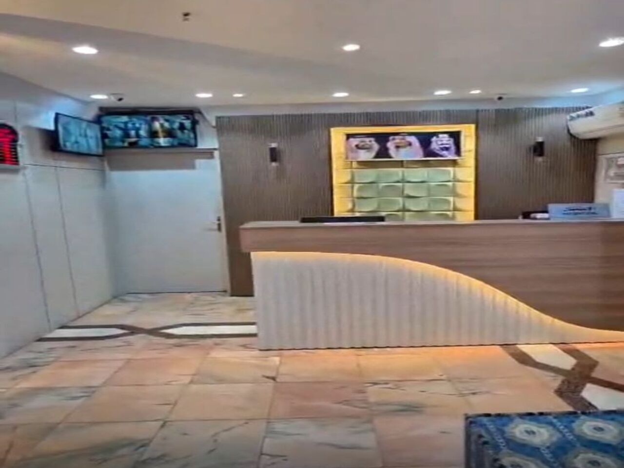 A reception area with a curved reception desk, a television mounted on the wall, and a patterned floor.
