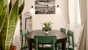 A dining area with a round table, green chairs, a potted plant, and a black and white photograph on the wall. - Flora Guest House (Rome)