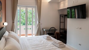 A hotel room with a bed, a desk, a chair, and a TV mounted on the wall. - Flora Guest House (Rome)