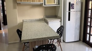 Eine kompakte Küche mit einer Granit-Arbeitsplatte, zwei schwarzen Stühlen, einer Mikrowelle und einem Kühlschrank.
