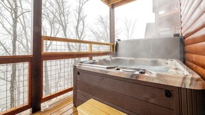 Ein Whirlpool in einer Holzhütte mit einer Holzterrasse und Blick auf Bäume.