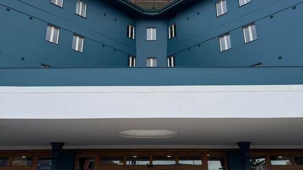 A building with a blue exterior, multiple windows, and a covered entrance area. - Naples Park Hotel (Marigliano)